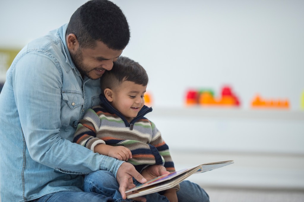A father and son are reading a book together.